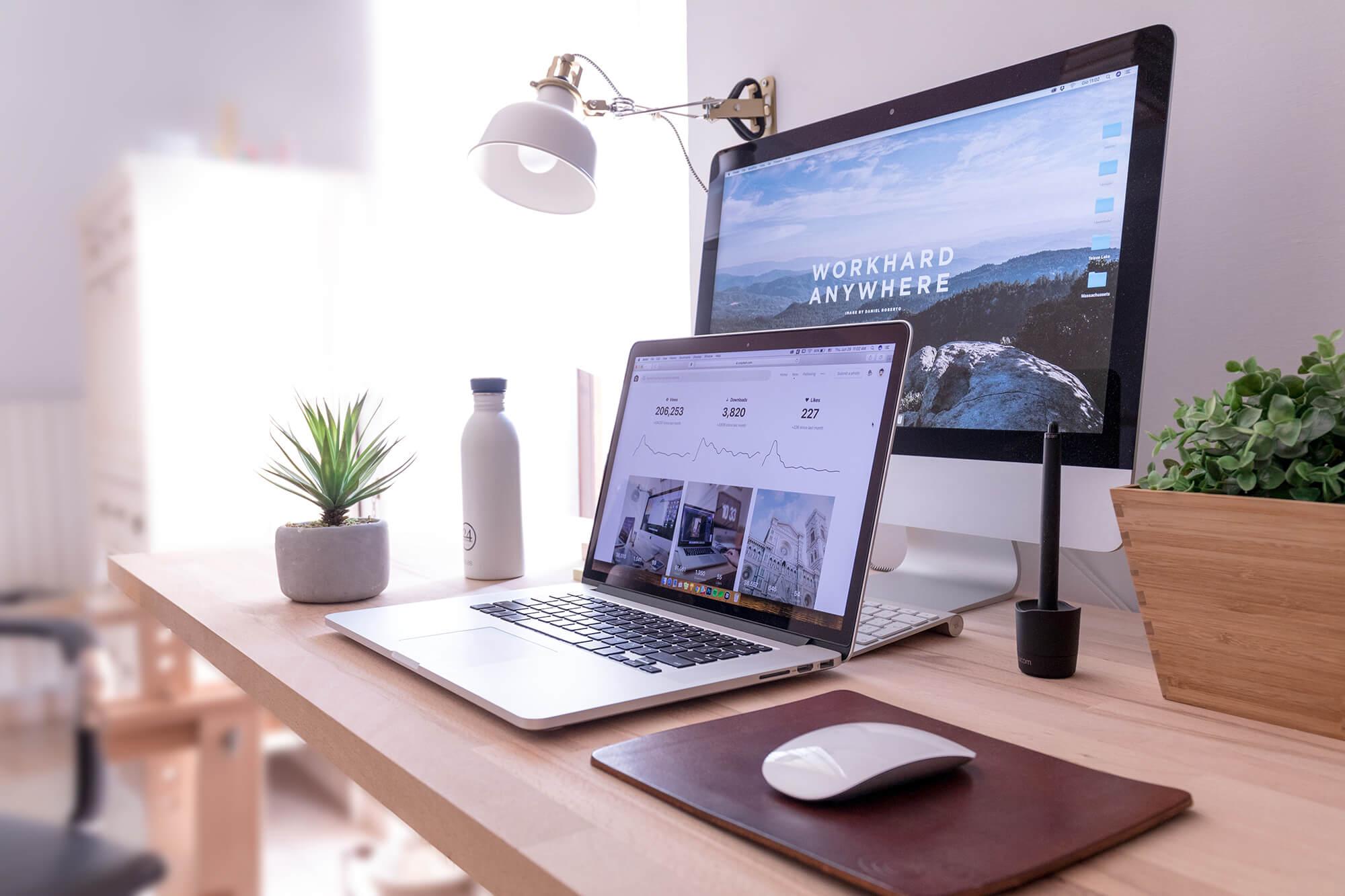 A photo displaying a computer screen with a landing page and a laptop displaying web analytics.
