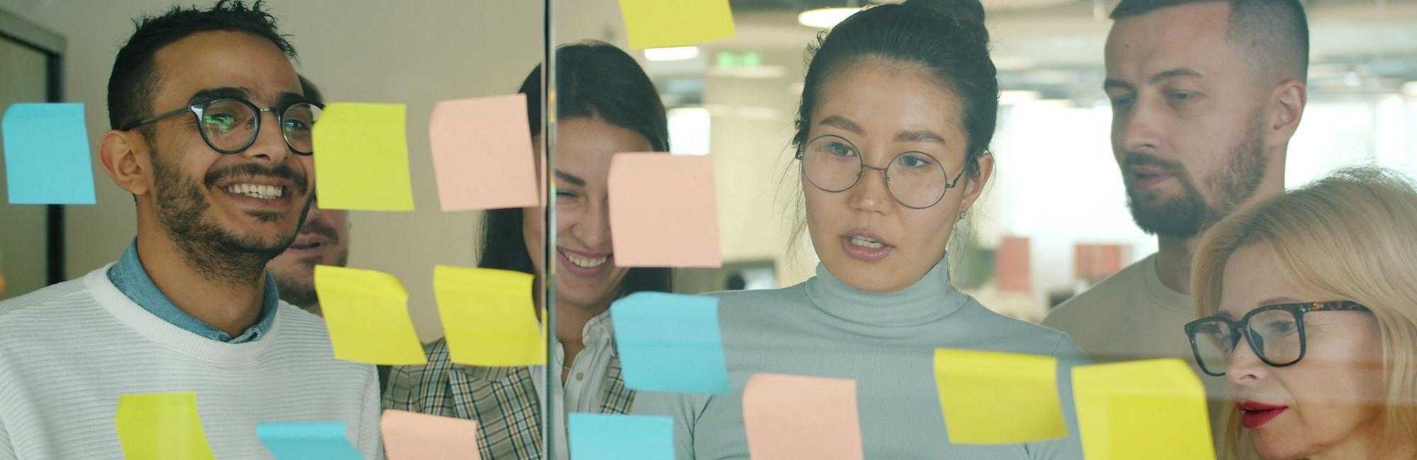Photograph of a group of people looking a asticky note-based mind map, planning out keywords.