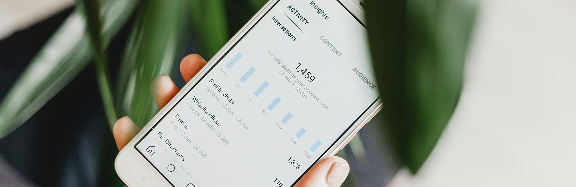 A close up photograph of a phone screen displaying performance marketing analytics.