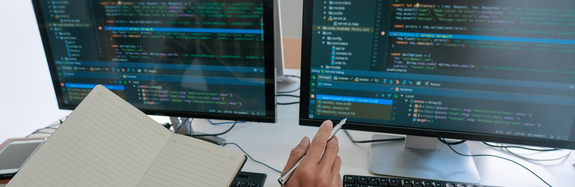 Photograph of a man in front of a computer, writing code.